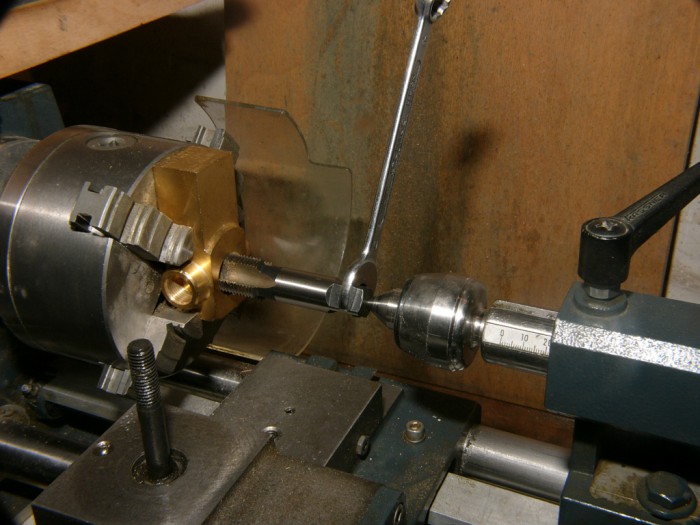 Mit diesem Aufbau kann man selbst größere Gewinde genau schneiden.  Der Gewindebohrer wird hinten im Rollkörner geführt. Mit einen Gabelschlüssel wird der Gewindebohrer ein paar erste Gänge eingedreht. Mit dem Reitstock drückt man den Gewindebohrer gefühlvoll nach.   Am Schraubstock wird danach das Gewinde mit einem Windeisen ganz eingedreht.  <br />Man sieht hier warum ich Vierbackenfutter bevorzuge, damit kann allerhand an der Drehbank gezaubert werden.